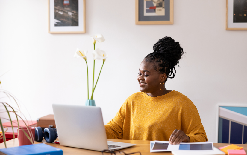 Smiling woman working on her laptop in a bright home office, representing online business tools for entrepreneurs.